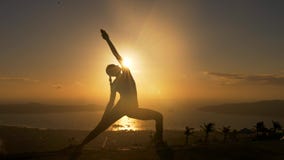 Silueta de la mujer que hace exersice de la aptitud de la yoga en la playa del mar en salida del sol metrajes Silueta de la mujer que hace exersice de la aptitud de la yoga en la playa del mar en salida del sol metrajes