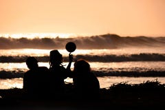 Silueta de los amigos jovenes que juegan con una bola en la playa en puesta del sol imagen de archivo libre de regalías Silueta de los amigos jovenes que juegan con una bola en la playa en puesta del sol imagen de archivo libre de regalías