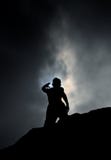 Silueta del hombre que se coloca en la roca que alcanza hasta el cielo durante eclipse parcial foto de archivo Silueta del hombre que se coloca en la roca que alcanza hasta el cielo durante eclipse parcial foto de archivo