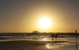 Siluetas de dos personas que practica surf en la puesta del sol en la playa foto de archivo libre de regalías Siluetas de dos personas que practica surf en la puesta del sol en la playa foto de archivo libre de regalías