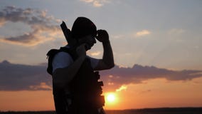 Siluetea al soldado con el arma contra una puesta del sol almacen de metraje de vídeo Siluetea al soldado con el arma contra una puesta del sol almacen de metraje de vídeo
