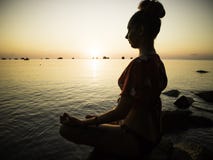 Siluetee la yoga practicante de la mujer joven en la playa en la puesta del sol fotos de archivo Siluetee la yoga practicante de la mujer joven en la playa en la puesta del sol fotos de archivo