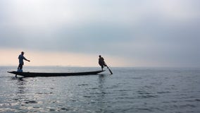 Siluetta dei pescatori che remano dalle gambe sul lago Inle, Myanmar immagini stock Siluetta dei pescatori che remano dalle gambe sul lago Inle, Myanmar immagini stock