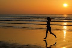 Siluetta di funzionamento del pareggiatore della donna sulla spiaggia di tramonto con la riflessione, la forma fisica e lo sport fotografia stock Siluetta di funzionamento del pareggiatore della donna sulla spiaggia di tramonto con la riflessione, la forma fisica e lo sport fotografia stock