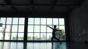 Siluetta di un maschio del ballerino di balletto contro lo sfondo di grande finestra Movimento lento archivi video Siluetta di un maschio del ballerino di balletto contro lo sfondo di grande finestra Movimento lento archivi video