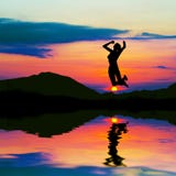 Siluetta della donna felice che salta al tramonto fotografia stock libera da diritti Siluetta della donna felice che salta al tramonto fotografia stock libera da diritti