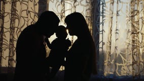 Siluetta di una famiglia felice È la casa dalla finestra al tramonto, delicatamente tiene il bambino nelle vostre armi Siluetta di una famiglia felice È la casa dalla finestra al tramonto, delicatamente tiene il bambino nelle vostre armi