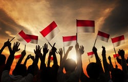Siluette della gente che tiene la bandiera dell'Indonesia fotografia stock libera da diritti Siluette della gente che tiene la bandiera dell'Indonesia fotografia stock libera da diritti