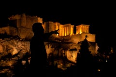 Siluette della gente nella priorità alta, con la vista di notte dell'acropoli ai precedenti fotografia stock Siluette della gente nella priorità alta, con la vista di notte dell'acropoli ai precedenti fotografia stock