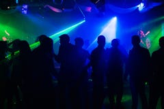 Siluette della gente sulla pista da ballo del night-club ai proiettori del laser immagini stock Siluette della gente sulla pista da ballo del night-club ai proiettori del laser immagini stock