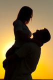 Siluette di giovani coppie nell'amore al tramonto fotografia stock Siluette di giovani coppie nell'amore al tramonto fotografia stock