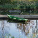 Simple wooden boat at the wooden pier on the pond. stock photo Simple wooden boat at the wooden pier on the pond. stock photo