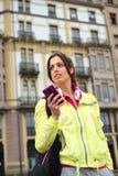Simsende Mitteilung der sportlichen städtischen Frau auf Smartphone in der Straße stockbild Simsende Mitteilung der sportlichen städtischen Frau auf Smartphone in der Straße stockbild