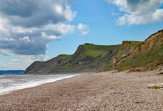 Singelstranden på Eype i Dorset på en solig dag, sandstenklipporna av den Jurassic kusten kan ses i bakgrunden arkivbilder Singelstranden på Eype i Dorset på en solig dag, sandstenklipporna av den Jurassic kusten kan ses i bakgrunden arkivbilder