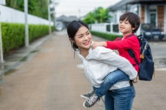 Single mom carrying and playing with her children near home with villa street background. People and Lifestyles concept. Happy stock image Single mom carrying and playing with her children near home with villa street background. People and Lifestyles concept. Happy stock image