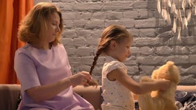 Sira de mãe a trançar seus cabelo, pai e criança pequenos do ` s da filha sentando-se junto no sofá, conceito de família dentro video estoque Sira de mãe a trançar seus cabelo, pai e criança pequenos do ` s da filha sentando-se junto no sofá, conceito de família dentro video estoque