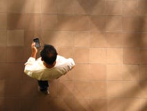 Sirva caminar y mandar un SMS en el teléfono móvil, visión aérea fotos de archivo libres de regalías Sirva caminar y mandar un SMS en el teléfono móvil, visión aérea fotos de archivo libres de regalías