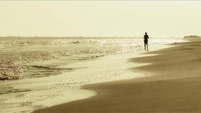 Sirva el funcionamiento en la playa en la puesta del sol Sirva el funcionamiento en la playa en la puesta del sol