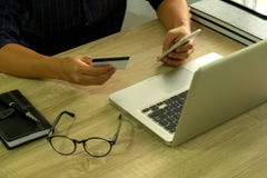 Sirva sostener la tarjeta de crédito y usar el smartphone para las compras del pago foto de archivo libre de regalías Sirva sostener la tarjeta de crédito y usar el smartphone para las compras del pago foto de archivo libre de regalías