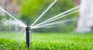 Sistema antincendio automatico che innaffia il prato inglese su un fondo di erba verde immagini stock libere da diritti Sistema antincendio automatico che innaffia il prato inglese su un fondo di erba verde immagini stock libere da diritti