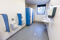 Sitio del retrete para los hombres con los fregaderos de los orinales y el dispensador de la toalla fotos de archivo libres de regalías Sitio del retrete para los hombres con los fregaderos de los orinales y el dispensador de la toalla fotos de archivo libres de regalías
