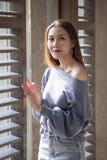 Situación hermosa de la mujer en una ventana de madera foto de archivo libre de regalías Situación hermosa de la mujer en una ventana de madera foto de archivo libre de regalías