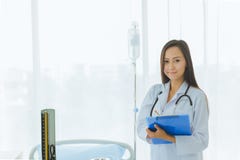 Situación y actitudes asiáticas del doctor cerca de la cama paciente Situación y actitudes asiáticas del doctor cerca de la cama foto de archivo Situación y actitudes asiáticas del doctor cerca de la cama paciente Situación y actitudes asiáticas del doctor cerca de la cama foto de archivo