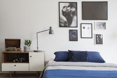 Skandinavische stijl, houten opmaker door een marineblauw bed en ontworpen kunstgalerie op een witte muur van een creatieve slaap stock afbeeldingen Skandinavische stijl, houten opmaker door een marineblauw bed en ontworpen kunstgalerie op een witte muur van een creatieve slaap stock afbeeldingen