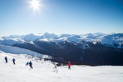 Skieurs sur une colline en haut de Blackcomb, 7ème ciel, avec une vue regardant vers Whistler un jour ensoleillé image stock Skieurs sur une colline en haut de Blackcomb, 7ème ciel, avec une vue regardant vers Whistler un jour ensoleillé image stock