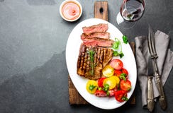 Skivad medelsällsynt grillad nötköttbiff tjänade som på den vita plattan med tomatsallad och potatisbollar Grillfest bbq-kött royaltyfri fotografi Skivad medelsällsynt grillad nötköttbiff tjänade som på den vita plattan med tomatsallad och potatisbollar Grillfest bbq-kött royaltyfri fotografi