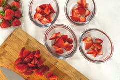 Skivade jordgubbar i klara exponeringsglasbunkar, skivade jordgubbar på en skärbräda, fruktsallad, efterrätt arkivfoto Skivade jordgubbar i klara exponeringsglasbunkar, skivade jordgubbar på en skärbräda, fruktsallad, efterrätt arkivfoto