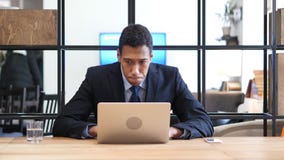 Skoncentrowany Czarny biznesmen Pracuje na laptopie zdjęcia stock Skoncentrowany Czarny biznesmen Pracuje na laptopie zdjęcia stock