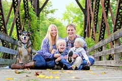 Skratta lyckligt familjsammanträde på bron i Autumn Forest arkivfoton Skratta lyckligt familjsammanträde på bron i Autumn Forest arkivfoton