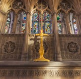 SKROV UK - 3RD MARS 2019: Ett gult målat kors sitter framme av målat glass i skrovdomkyrkan arkivbild SKROV UK - 3RD MARS 2019: Ett gult målat kors sitter framme av målat glass i skrovdomkyrkan arkivbild