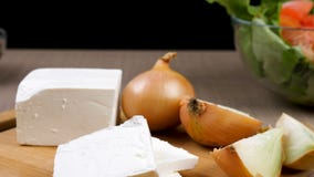 Skupia się tropiący dolly na pomidorach sałatkowych z zielonej sałatki lefs, cebulą i feta serem na drewnianej desce, zbiory Skupia się tropiący dolly na pomidorach sałatkowych z zielonej sałatki lefs, cebulą i feta serem na drewnianej desce, zbiory
