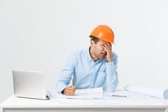 Skupiający się poważnego pracowitego inżyniera ruchliwie działanie na dużym architektonicznym projekcie póżno, siedzący przy jego zdjęcie stock Skupiający się poważnego pracowitego inżyniera ruchliwie działanie na dużym architektonicznym projekcie póżno, siedzący przy jego zdjęcie stock