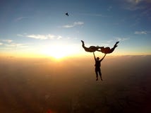 Skydivers que se divierten en la puesta del sol fotografía de archivo Skydivers que se divierten en la puesta del sol fotografía de archivo