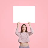 Slank härlig Caucasian kvinna i tillfällig kläder, vitt kort för hållvitmellanrum för din annonsering eller befordrings- innehåll arkivbild Slank härlig Caucasian kvinna i tillfällig kläder, vitt kort för hållvitmellanrum för din annonsering eller befordrings- innehåll arkivbild