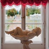 Catherine Palace, awaking Cherub laying in bowl in front of window with view to park of Catherine Palace, St. Petersburg, Russia