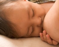 Sleepy baby boy enjoying breastfeeding
