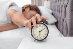 Sleepy man turning off alarm clock in morning stock images Sleepy man turning off alarm clock in morning stock images