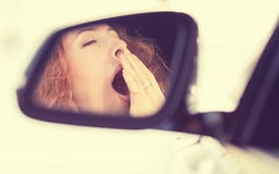 Sleepy tired fatigued yawning exhausted woman driving her car