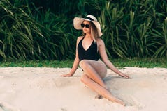 Slender young beautiful girl in black body posing on the beach, wearing a fashionable hat with wide brim, enjoying royalty free stock images Slender young beautiful girl in black body posing on the beach, wearing a fashionable hat with wide brim, enjoying royalty free stock images