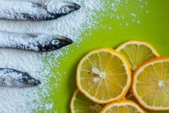 Slices of lemon and small silver fish sprinkled with flour on a green table stock image Slices of lemon and small silver fish sprinkled with flour on a green table stock image
