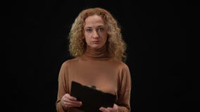 Slim Caucasian beautiful woman turning to camera with serious facial expression holding documents. Portrait of confident
