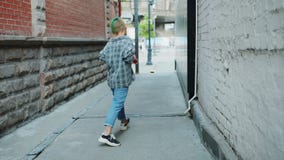 Slow motion of Asian teenager enjoying skateboarding in city street smiling
