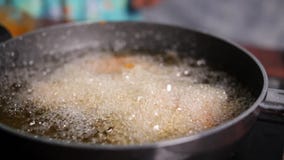 Slow motion closeup of cooking oil boiling in a shallow pan