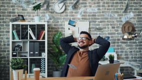 Slow motion of lots of money falling on handsome middle-aged guy in office stock video Slow motion of lots of money falling on handsome middle-aged guy in office stock video