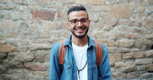 Slow motion portrait of charismatic Arabian man smiling outdoors near brick wall stock video Slow motion portrait of charismatic Arabian man smiling outdoors near brick wall stock video