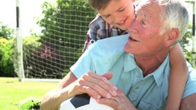 Slow Motion Shot Of Grandfather And Grandson With Football